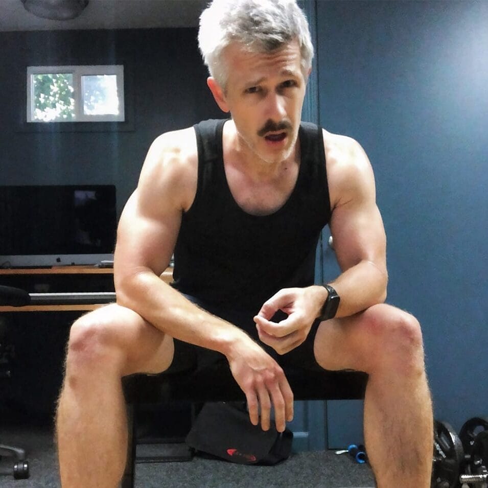 Nate Clark resting with dumbbells in his home office during the pandemic